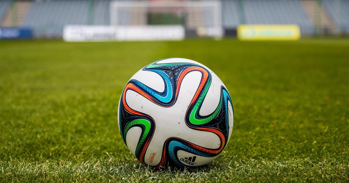Piłkarze podczas treningu na boisku klubu sportowego z widoczną infrastrukturą