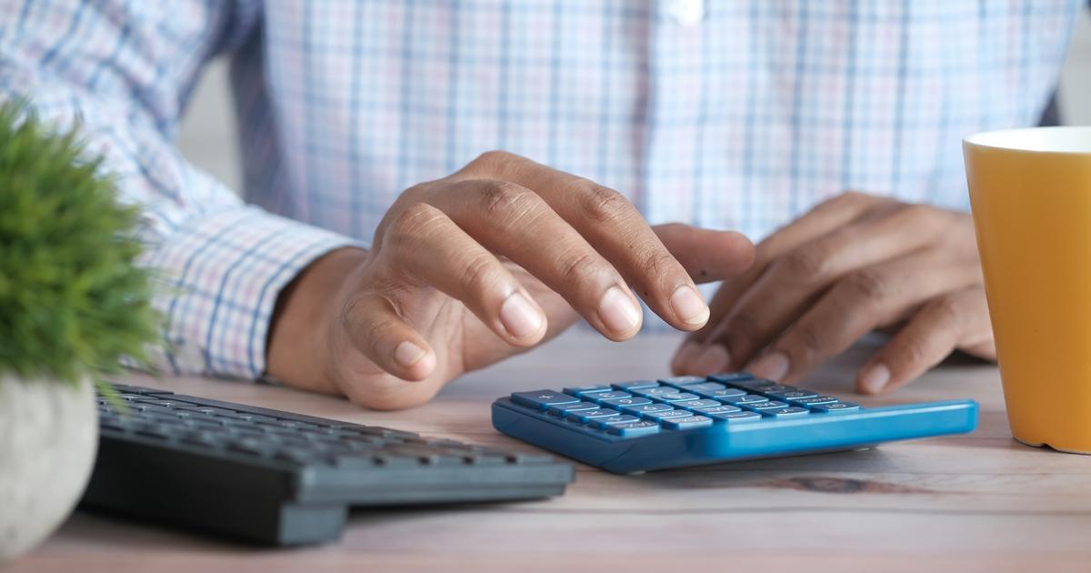 Księgowa wykonuje obliczenia na kalkulatorze przy biurku z klawiaturą