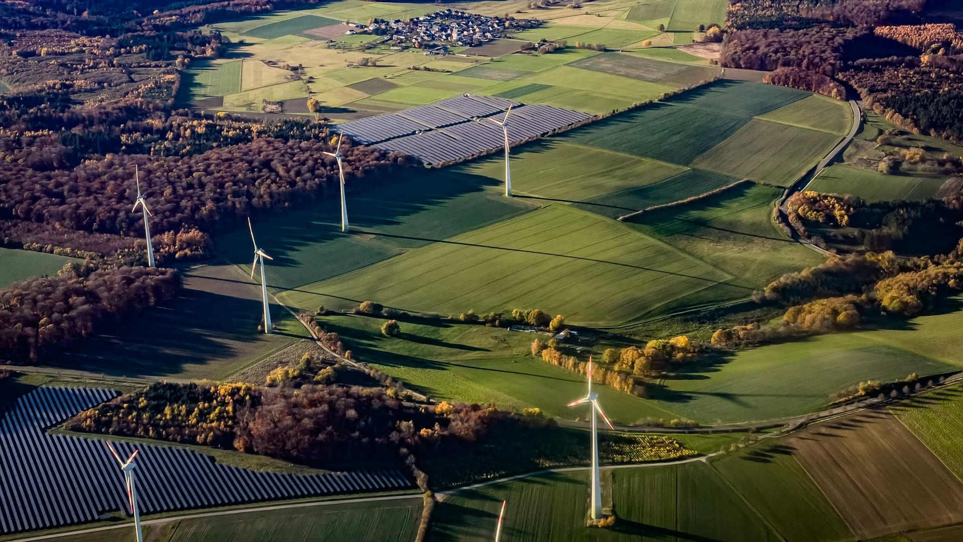 Wiatraki i panele fotowoltaiczne w krajobrazie wiejskim symbolizujące branżę odnawialnych źródeł energii, w której działała upadła spółka objęta inwentaryzacją środków trwałych dla syndyka masy upadłościowej